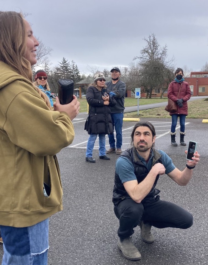 Travis crouched on the ground holding a phone to record